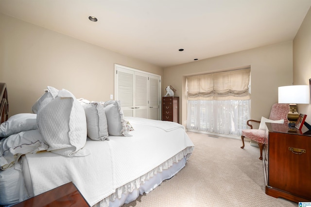 bedroom with recessed lighting, a closet, and light carpet