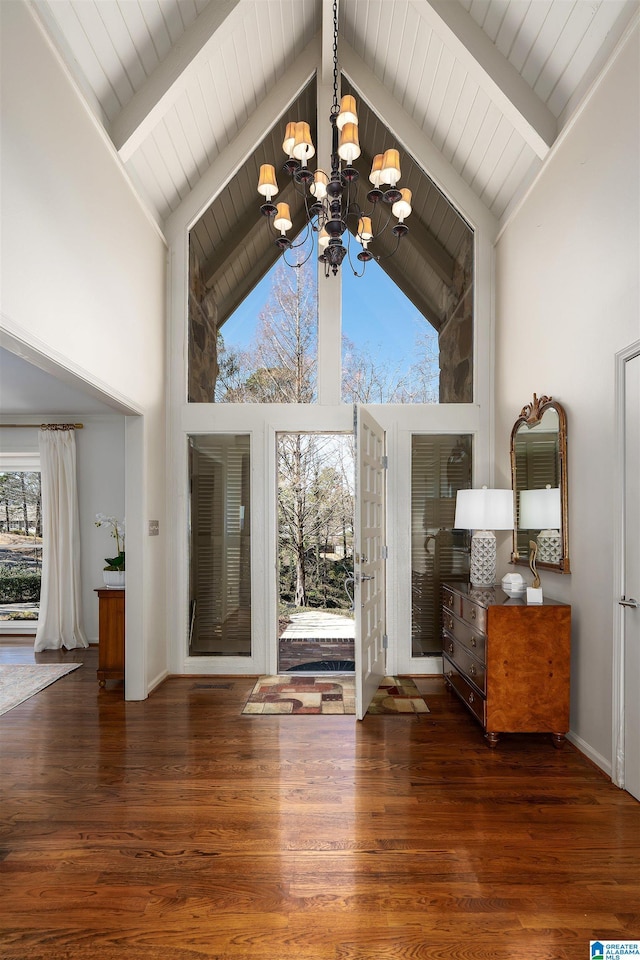 interior space with a notable chandelier, wood finished floors, and beamed ceiling