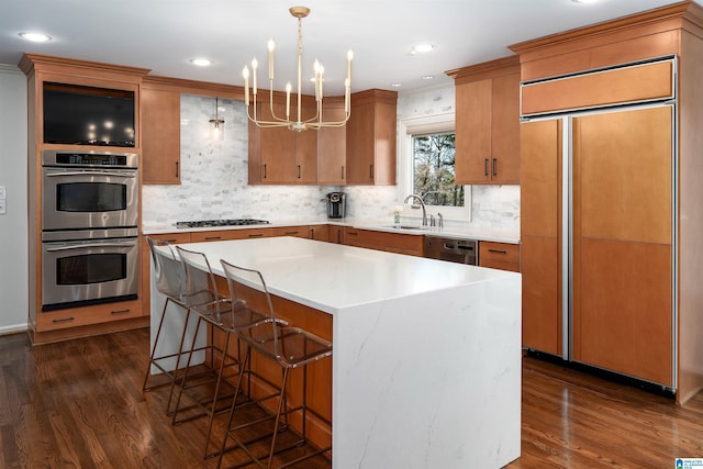 kitchen with a breakfast bar area, appliances with stainless steel finishes, dark wood-type flooring, and a sink