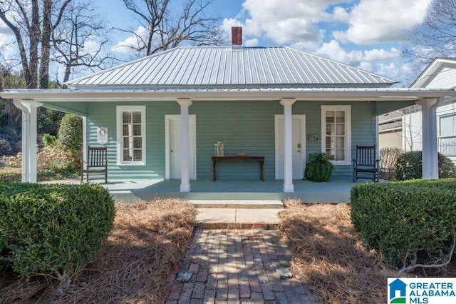 view of front of house with covered porch, metal roof, and a chimney