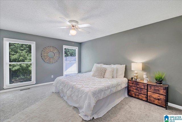 bedroom featuring a textured ceiling, ceiling fan, visible vents, baseboards, and carpet