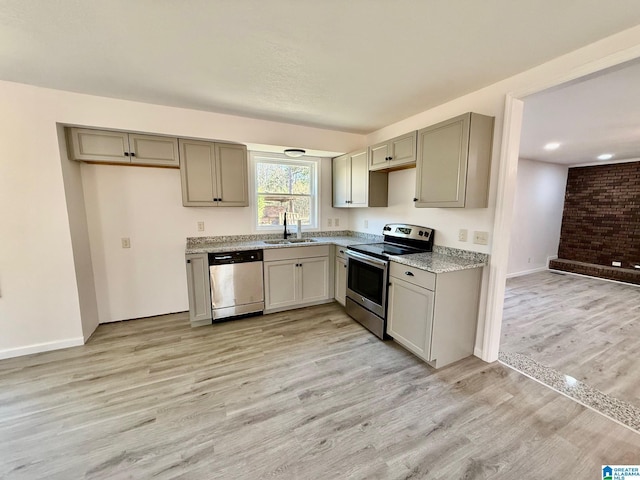 kitchen featuring appliances with stainless steel finishes, light wood-style floors, gray cabinets, and a sink