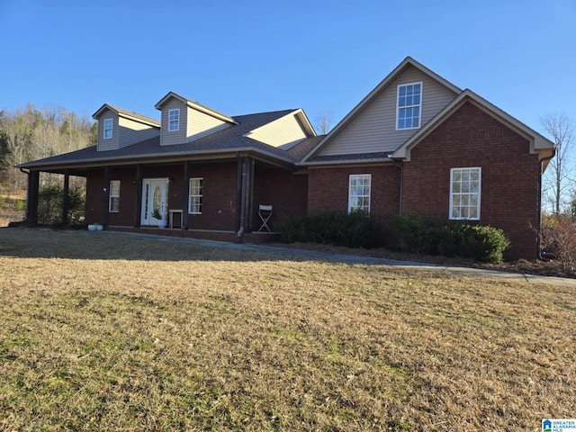 view of front facade featuring a front yard, covered porch, and brick siding