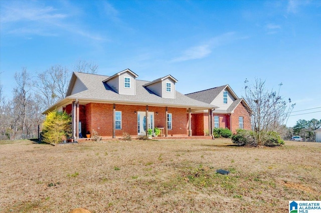 view of front facade with a porch, a front yard, and brick siding