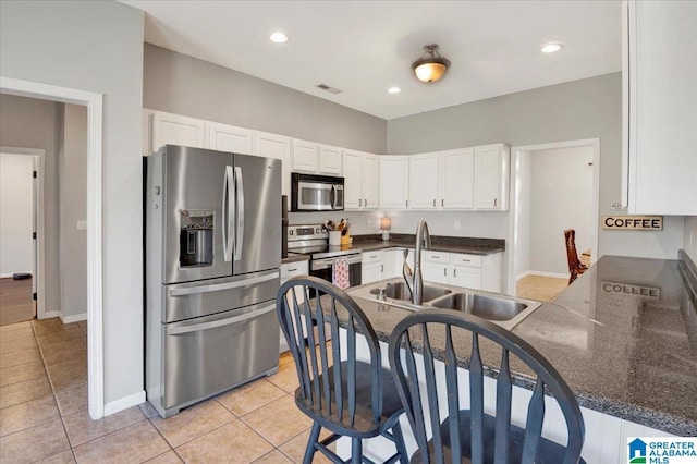 kitchen with appliances with stainless steel finishes, dark countertops, white cabinets, and a sink