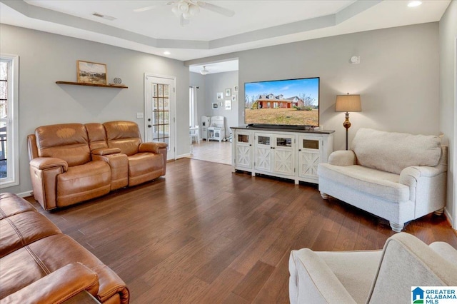 living room with a raised ceiling, plenty of natural light, and wood finished floors