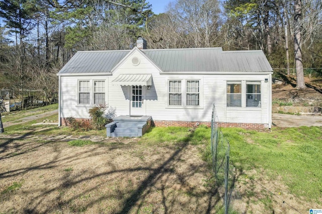 rear view of house featuring metal roof, a lawn, and a chimney