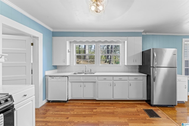 kitchen featuring visible vents, range, dishwasher, freestanding refrigerator, and a sink