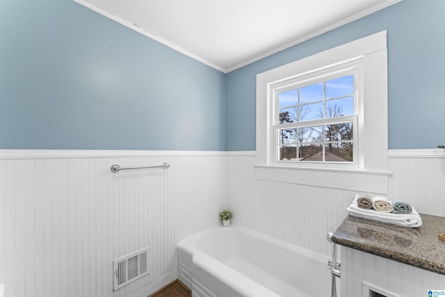 bathroom with a wainscoted wall, visible vents, and a bath