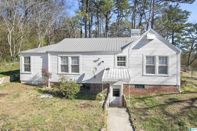 view of front of house with metal roof, a chimney, and a front lawn