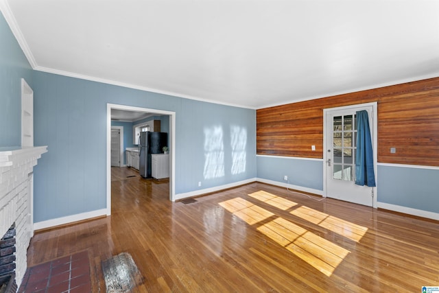 unfurnished living room featuring ornamental molding, a fireplace, wood-type flooring, and baseboards