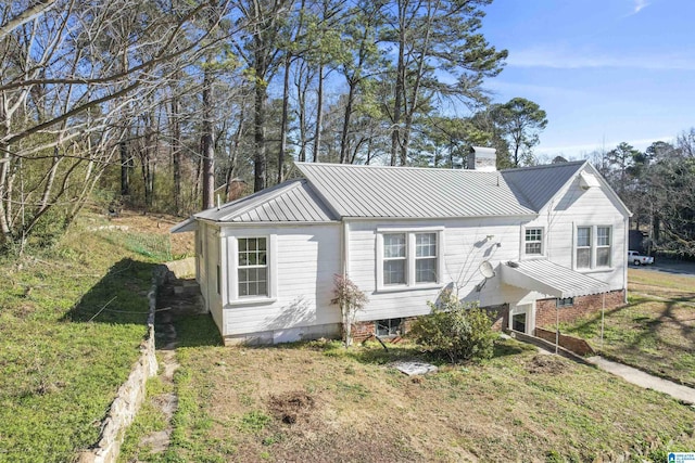 view of front of home with a standing seam roof, a chimney, and metal roof