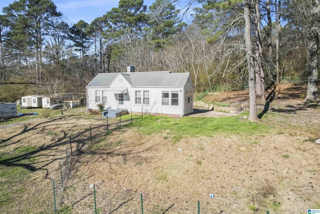 back of house featuring metal roof, a yard, and a chimney