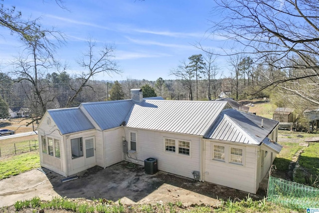 back of house with a patio area, a chimney, fence, and metal roof