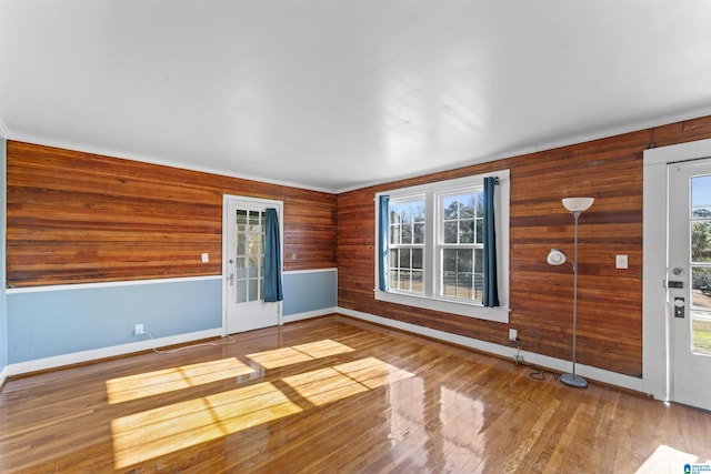 spare room with wood walls, baseboards, and hardwood / wood-style floors