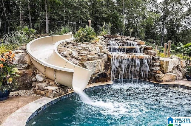 outdoor pool with fence and a water slide