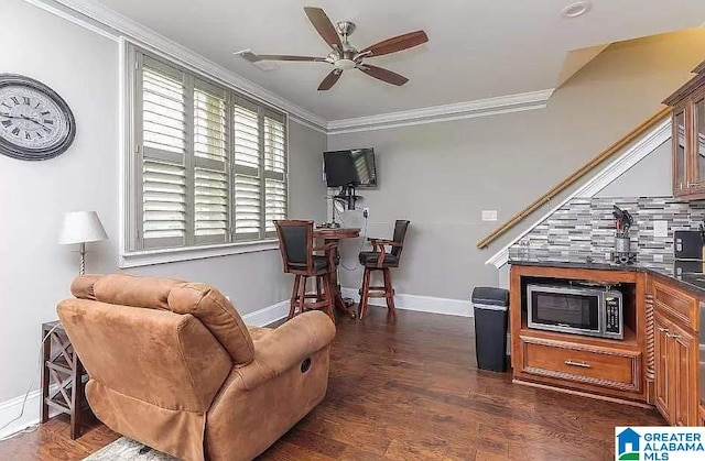 interior space featuring ornamental molding, dark wood-style flooring, a ceiling fan, and baseboards