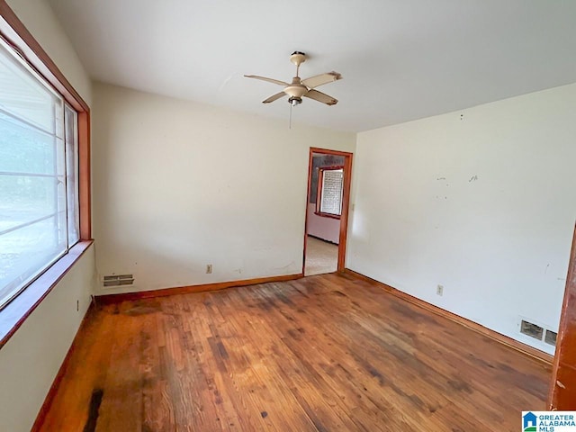 spare room featuring baseboards, ceiling fan, visible vents, and wood finished floors