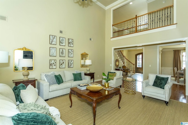 living room with ornamental molding, wood finished floors, visible vents, and stairs