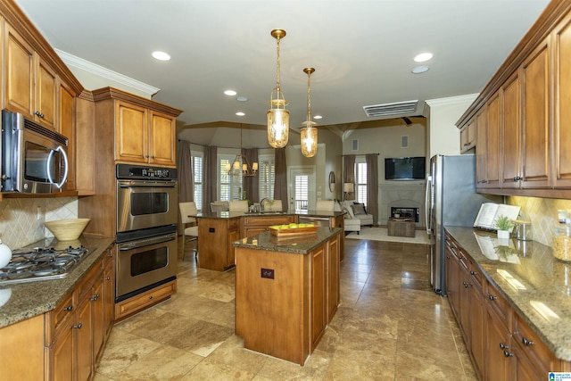 kitchen with a center island, brown cabinets, appliances with stainless steel finishes, open floor plan, and a sink