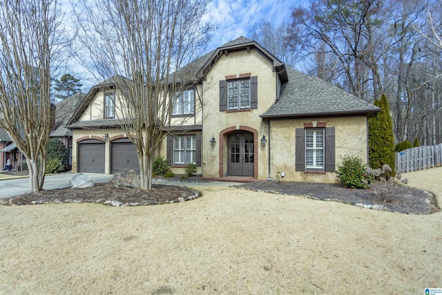 view of front facade with a garage, fence, driveway, roof with shingles, and stucco siding