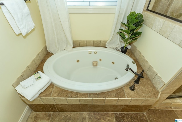 bathroom featuring a tub with jets and stone tile floors