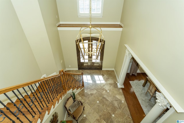 foyer entrance featuring a towering ceiling, an inviting chandelier, stairway, and baseboards