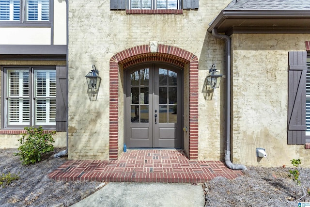 doorway to property featuring french doors, roof with shingles, and stucco siding