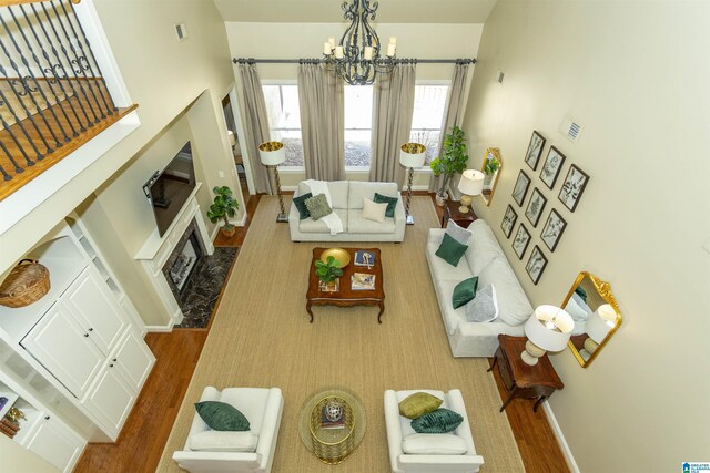 living area featuring visible vents, baseboards, wood finished floors, an inviting chandelier, and a fireplace