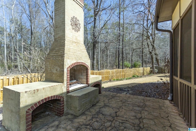 view of patio / terrace featuring an outdoor brick fireplace and fence