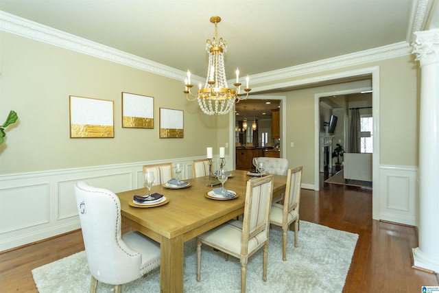 dining room with ornamental molding, wood finished floors, decorative columns, and a notable chandelier