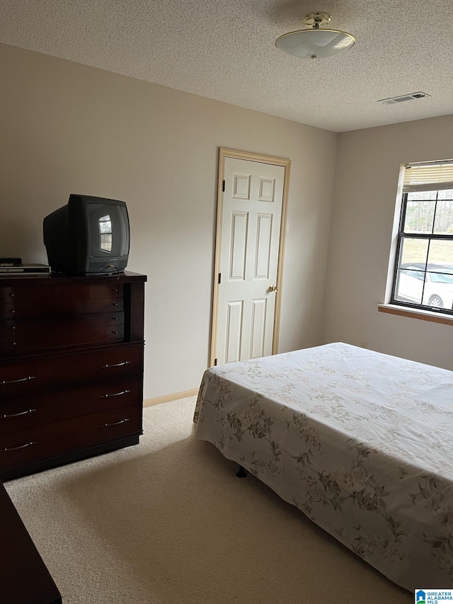 carpeted bedroom featuring baseboards, visible vents, and a textured ceiling