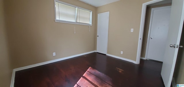 unfurnished bedroom with dark wood-style floors and baseboards