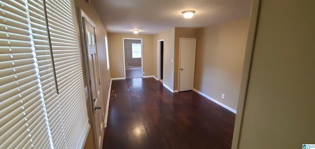 corridor featuring visible vents, baseboards, and wood finished floors