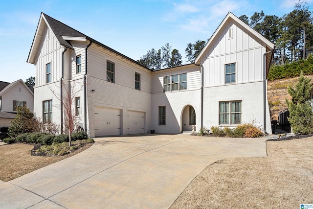 modern farmhouse featuring board and batten siding, concrete driveway, brick siding, and a garage