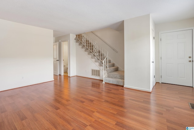 interior space featuring stairway, baseboards, visible vents, and wood finished floors