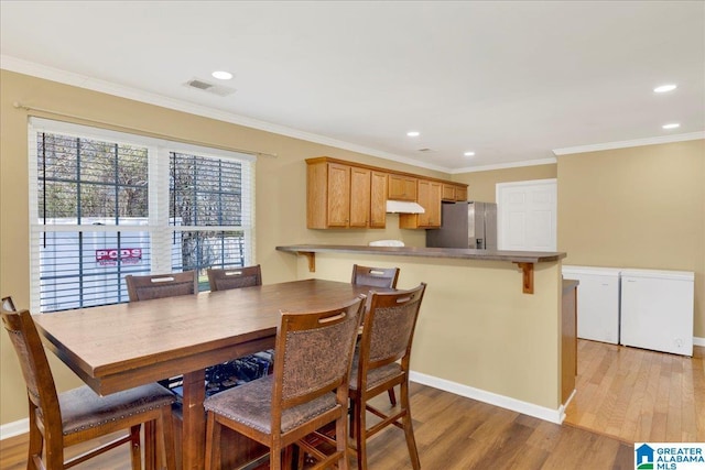 dining room featuring light wood-style floors, visible vents, and ornamental molding