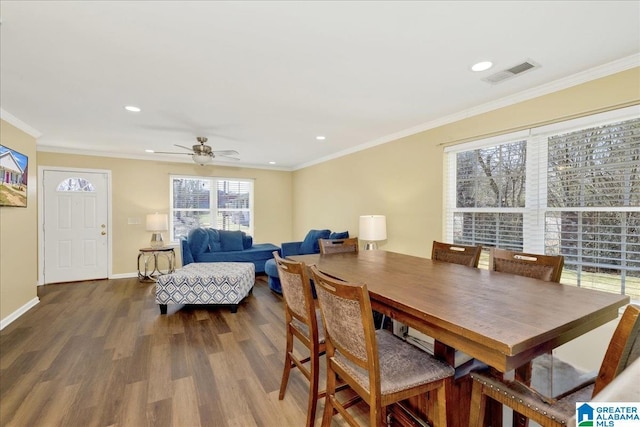 dining room with ornamental molding, visible vents, baseboards, and wood finished floors