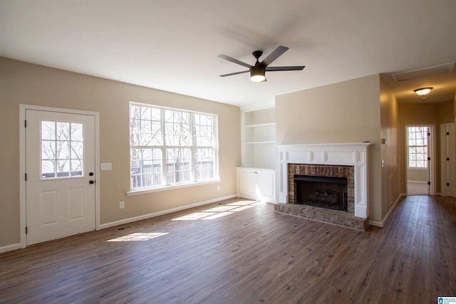 unfurnished living room featuring built in shelves, a fireplace, wood finished floors, and baseboards