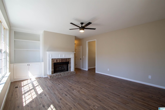 unfurnished living room featuring a wealth of natural light, dark wood finished floors, a fireplace, and baseboards