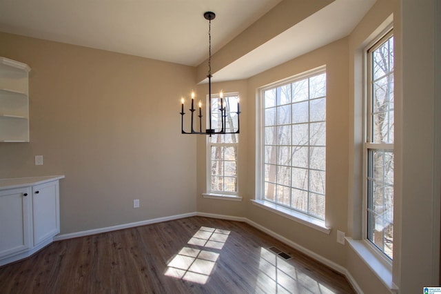 unfurnished dining area featuring dark wood-type flooring, plenty of natural light, visible vents, and baseboards