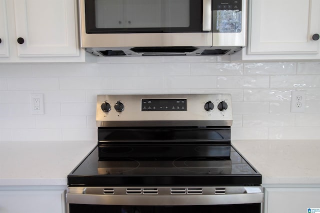 kitchen featuring light stone countertops, appliances with stainless steel finishes, white cabinets, and backsplash