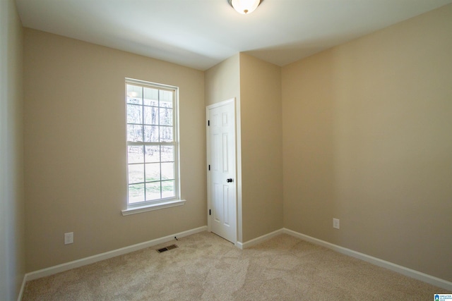 spare room featuring baseboards, visible vents, and light colored carpet