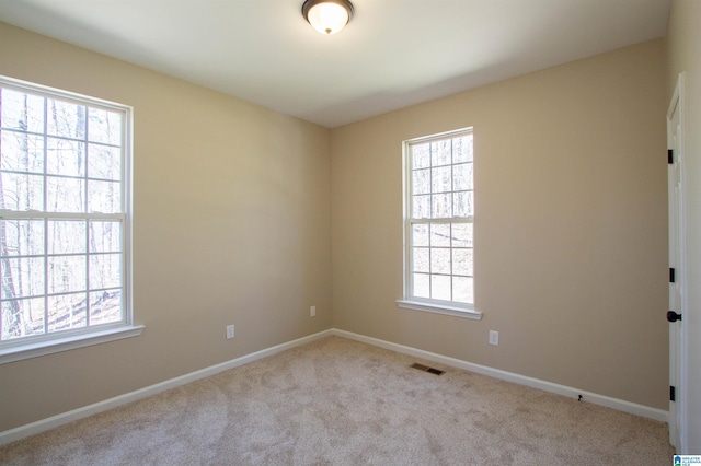 spare room with carpet floors, visible vents, baseboards, and a wealth of natural light