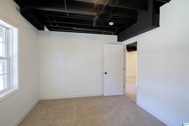 below grade area featuring a healthy amount of sunlight, baseboards, and carpet flooring