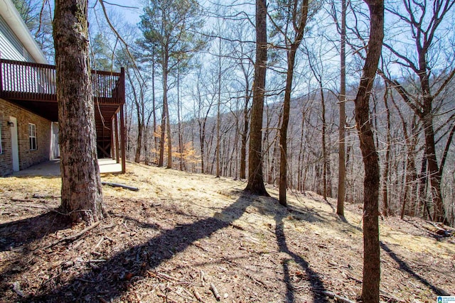 view of yard featuring a deck and a view of trees