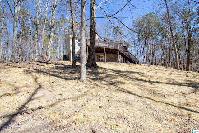 view of yard featuring stairs, a wooden deck, and a view of trees