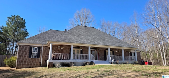 view of front of home featuring covered porch, brick siding, and a shingled roof