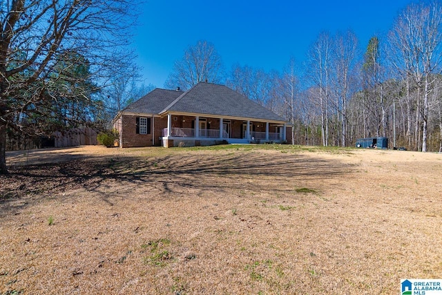 view of front of home with a porch, brick siding, and a front lawn