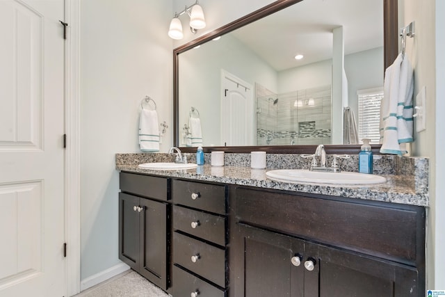 full bath featuring double vanity, a shower stall, baseboards, and a sink